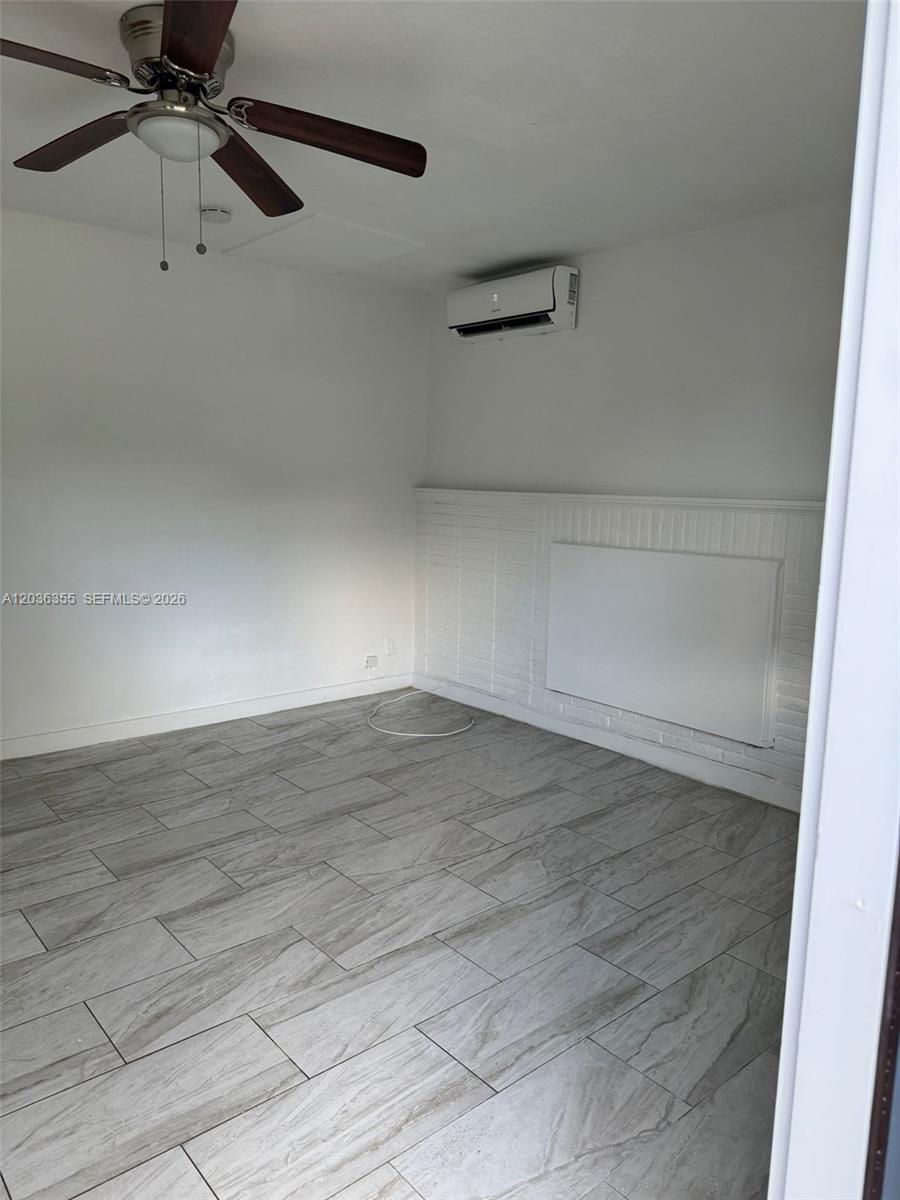 A room with gray wood-look tile flooring, a ceiling fan, and a wall-mounted air conditioner — 1324 N 58 AVE, Hollywood FL 33021, HOLLYWOOD, FL