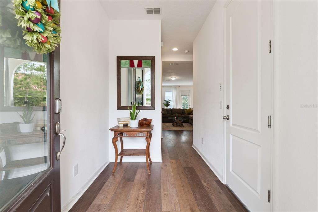 An entryway features wood-look flooring, a small wooden table with a mirror, and a white door — 2583 CIRCOLO LANE, APOPKA, FL
