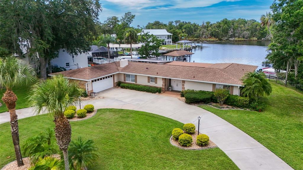 An aerial view of a single-story house with a concrete driveway and waterfront backyard — 1202 SE KINGS BAY DRIVE, CRYSTAL RIVER, FL