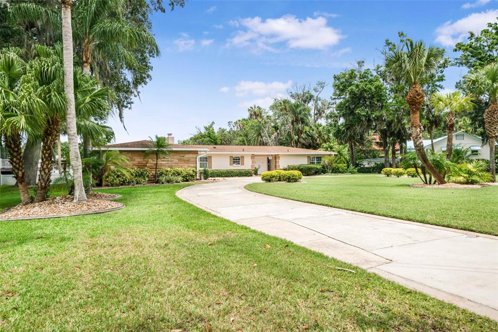 A single-story house with a stone facade and a curved concrete driveway on a lawn — 1202 SE KINGS BAY DRIVE, CRYSTAL RIVER, FL