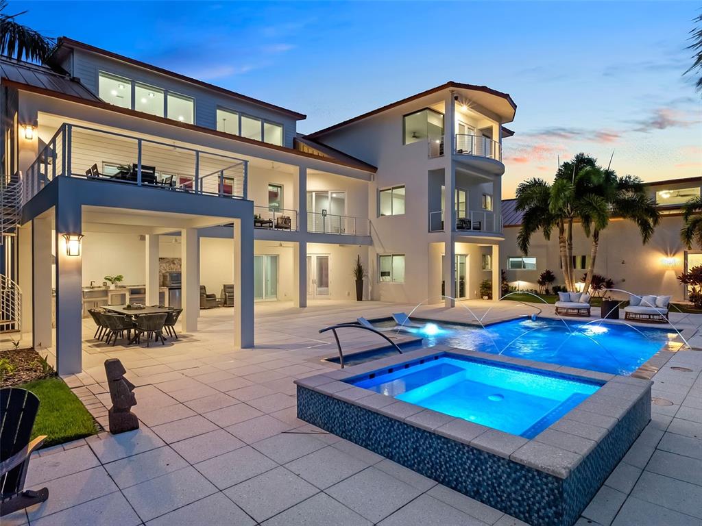 A multi-story house with a pool, hot tub, and covered patio at dusk — 1511 S RIVERSIDE DRIVE, NEW SMYRNA BEACH, FL