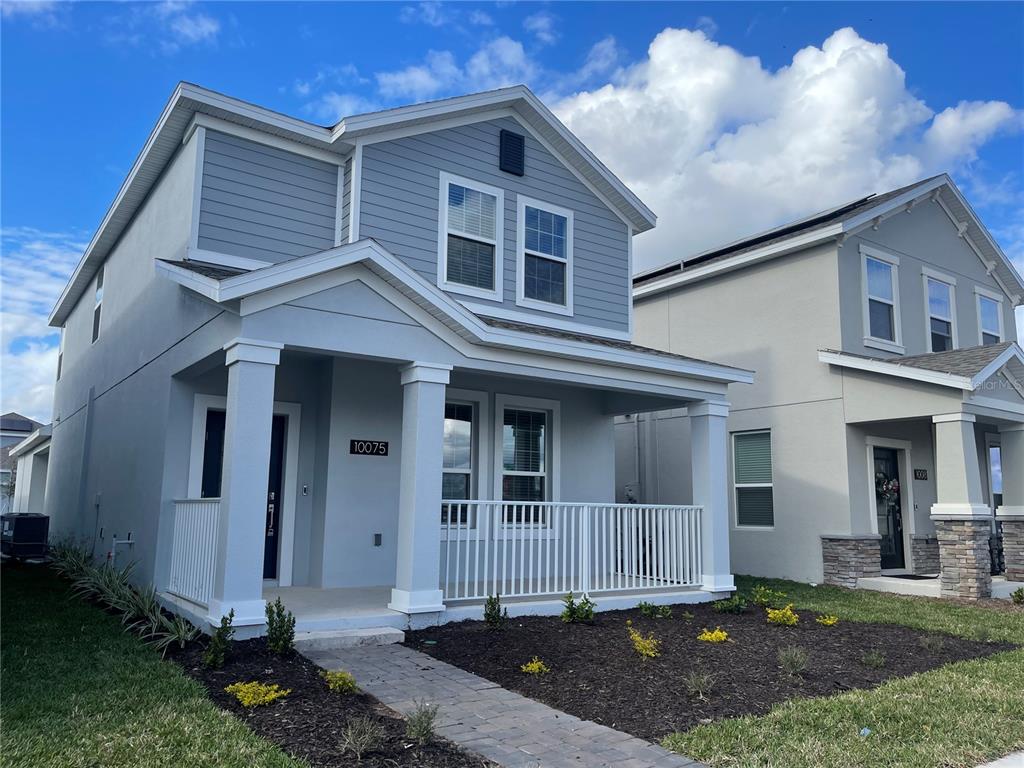 A two-story house with light blue siding, a covered front porch, and a paved walkway — 9777 PETITION WAY, ORLANDO, FL