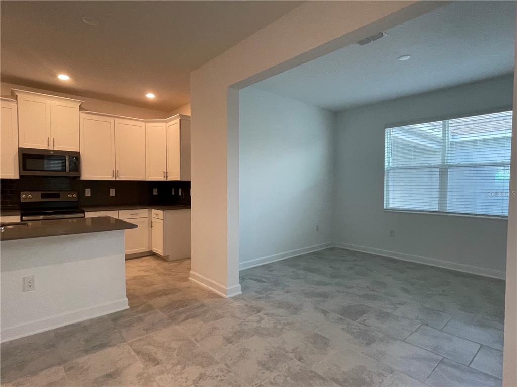 A kitchen with white cabinets and a breakfast area with tile flooring and a window — 9777 PETITION WAY, ORLANDO, FL