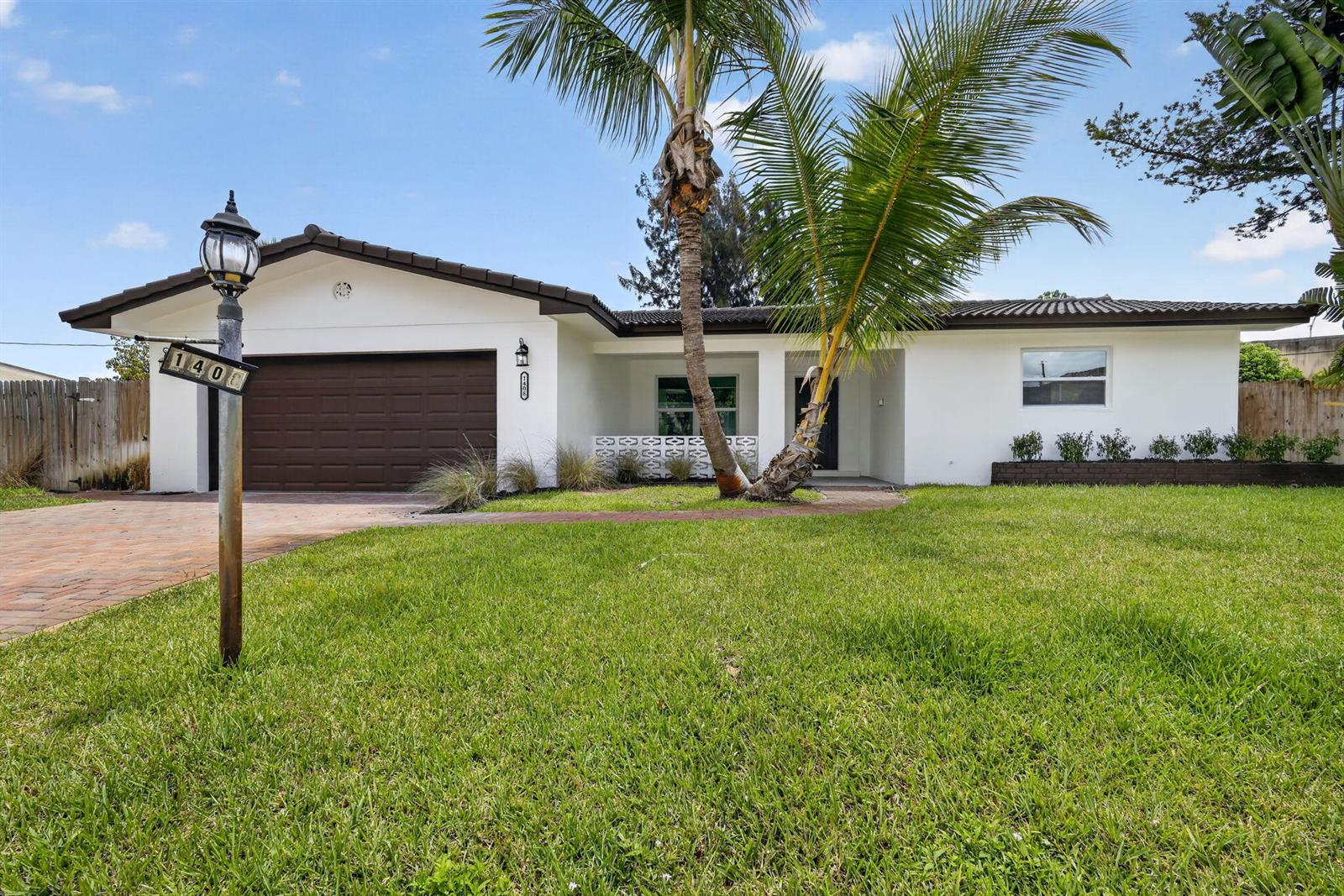 A single-story white house with a brown garage door, a palm tree, and a lawn — 1408 Cochran Drive, FL 33461, FL