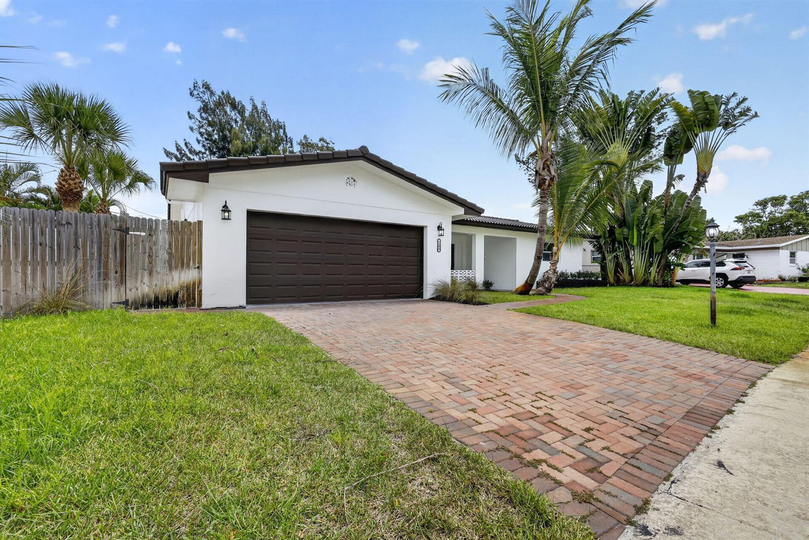 A single-story house features a white exterior, a brown garage door, and a brick driveway — 1408 Cochran Drive, FL 33461, FL