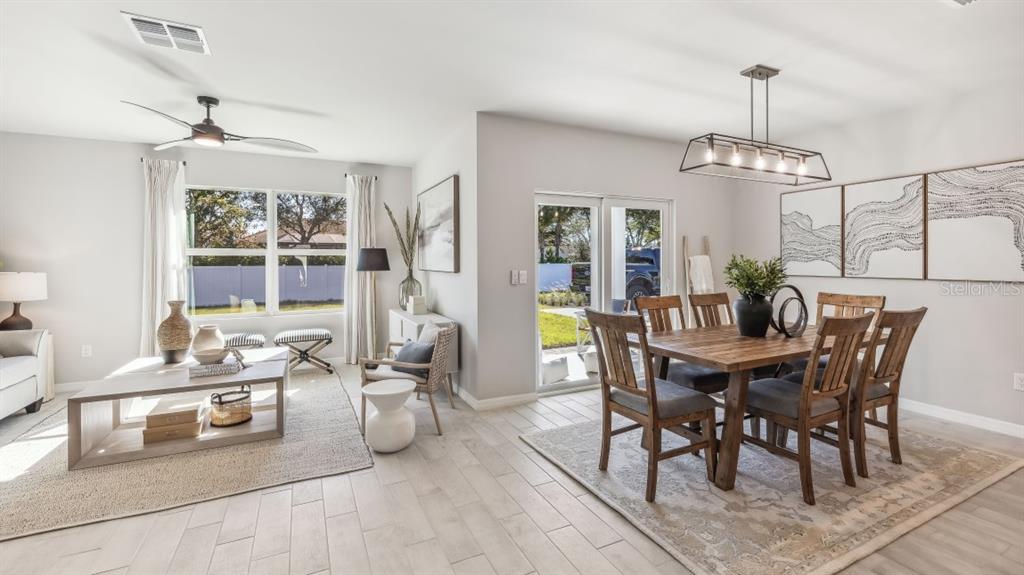A bright open-concept living and dining area features light wood-look tile flooring and sliding doors — 26227 CORAL LAKES DRIVE, PUNTA GORDA, FL