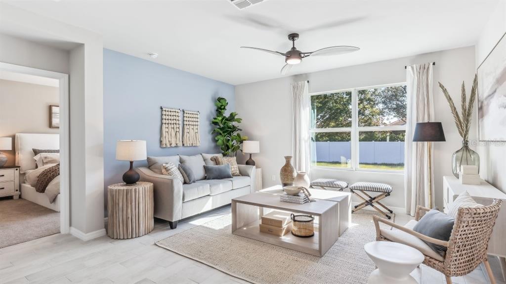 A living room features a light blue accent wall, a sofa, and a coffee table — 26227 CORAL LAKES DRIVE, PUNTA GORDA, FL