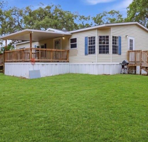 A single-story manufactured home with light siding, blue shutters, and a large wooden deck — 4524 SW 162ND TERRACE, OCALA, FL