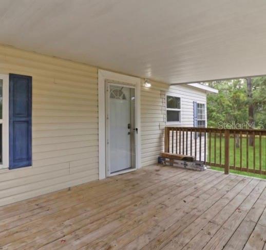 A wooden deck with a covered porch leads to a white front door with shutters — 4524 SW 162ND TERRACE, OCALA, FL