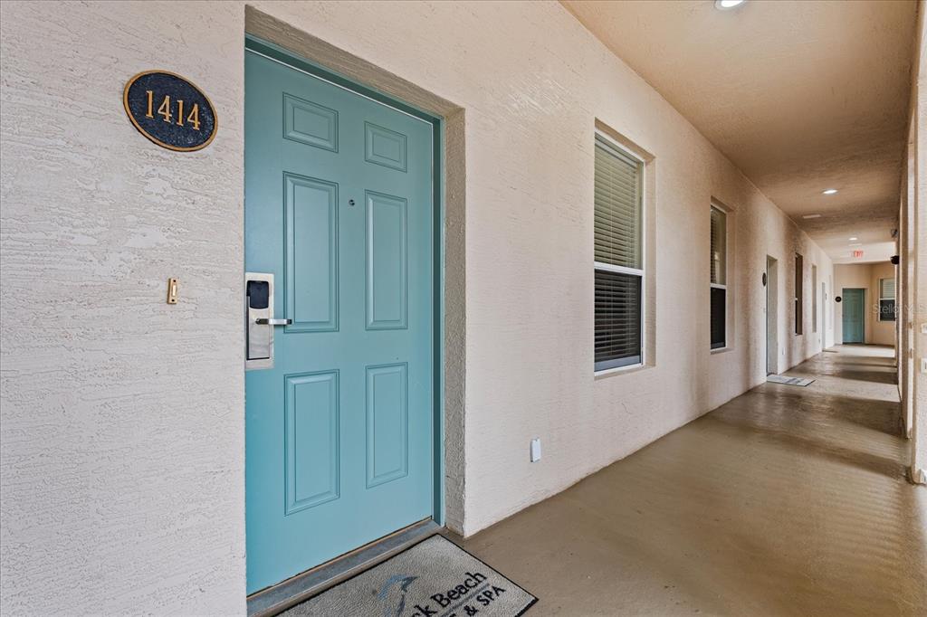 A teal door with a digital lock and the number 1414 sits along an outdoor hallway — 5 OCEAN CREST WAY UNIT 1414, PALM COAST, FL