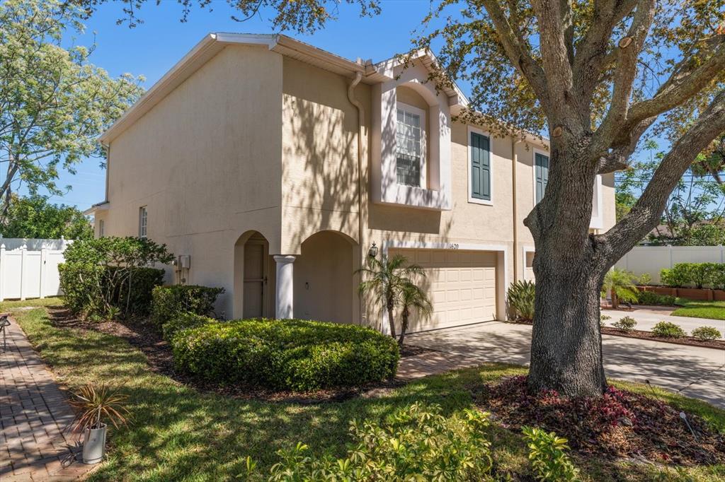 A two-story beige townhouse with a two-car garage and a large tree in the front — 1620 RACHEL COURT, CLEARWATER, FL