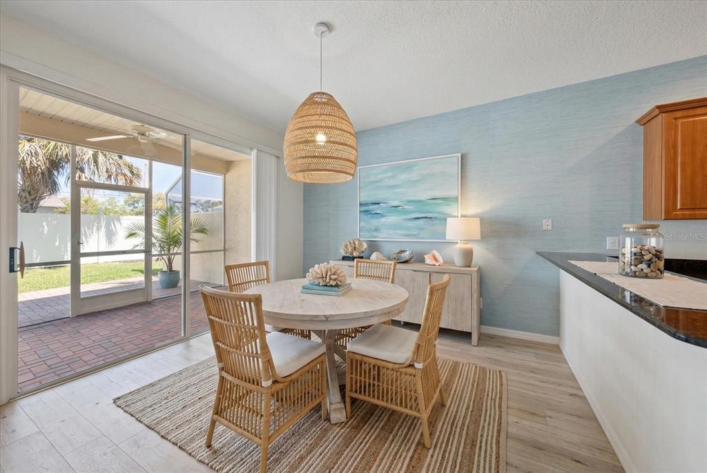 A dining area features a round wooden table, rattan chairs, and a blue textured wall — 1620 RACHEL COURT, CLEARWATER, FL