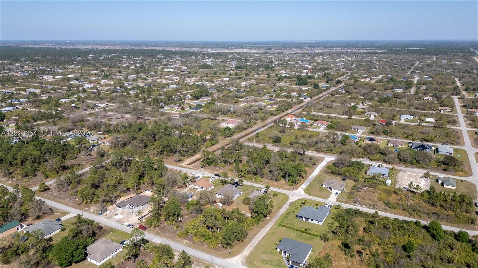 An aerial view shows a residential neighborhood with scattered houses, dirt roads, and wooded lots — 2522 W 53RD ST, Lehigh Acres FL 33971, LEHIGH ACRES, FL