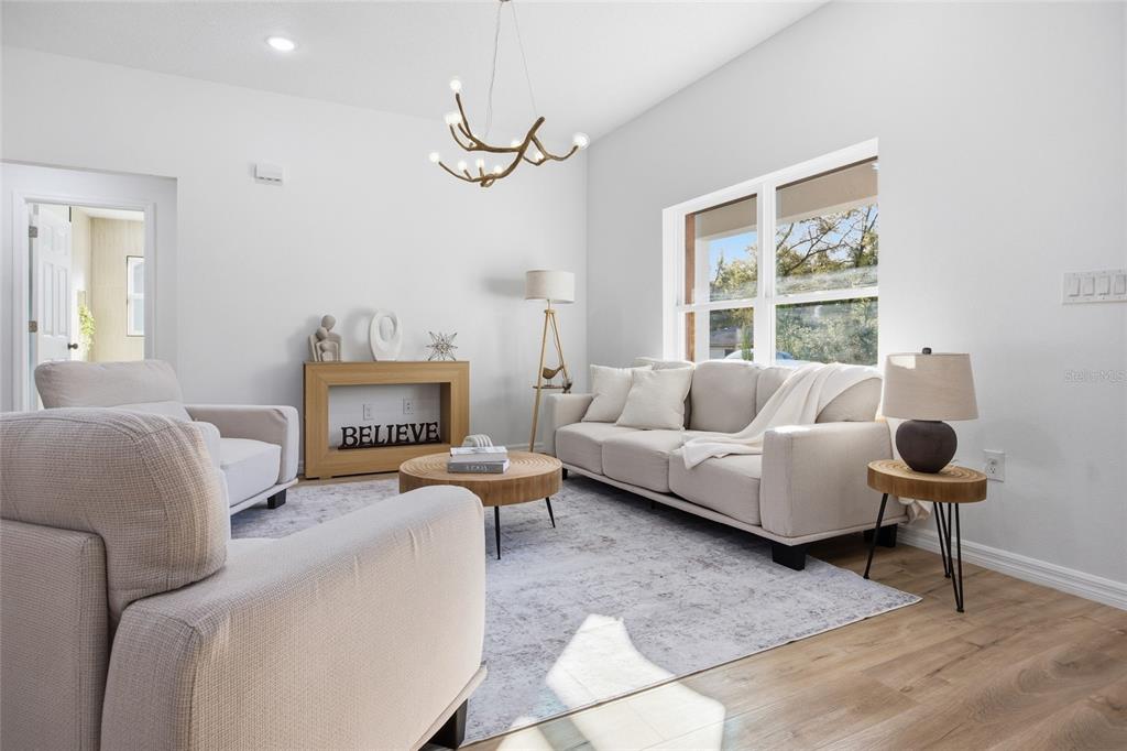 A bright living room features a beige sofa, two armchairs, a round coffee table, and a chandelier — 2116 W BEACH PLUM DRIVE, CITRUS SPRINGS, FL