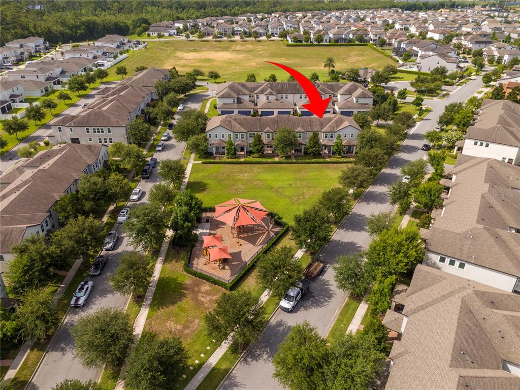 An aerial view shows a residential townhouse complex situated next to a community playground — 14031 PICARD ALLEY, WINTER GARDEN, FL