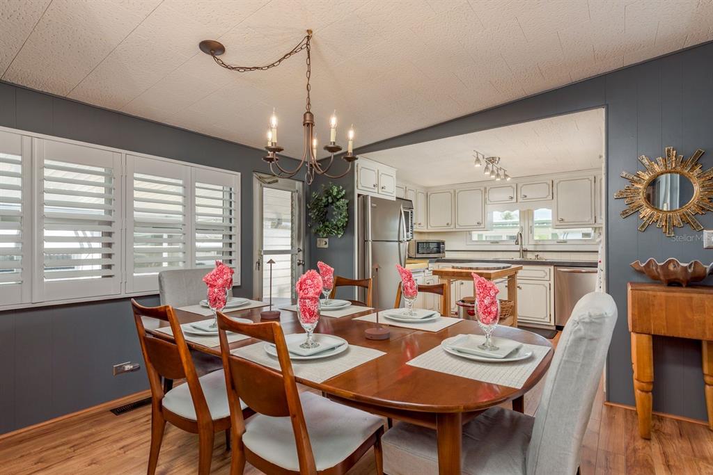 A dining room with a wooden table, chairs, and a chandelier, opening into a kitchen — 2331 BELLEAIR ROAD UNIT 906, CLEARWATER, FL