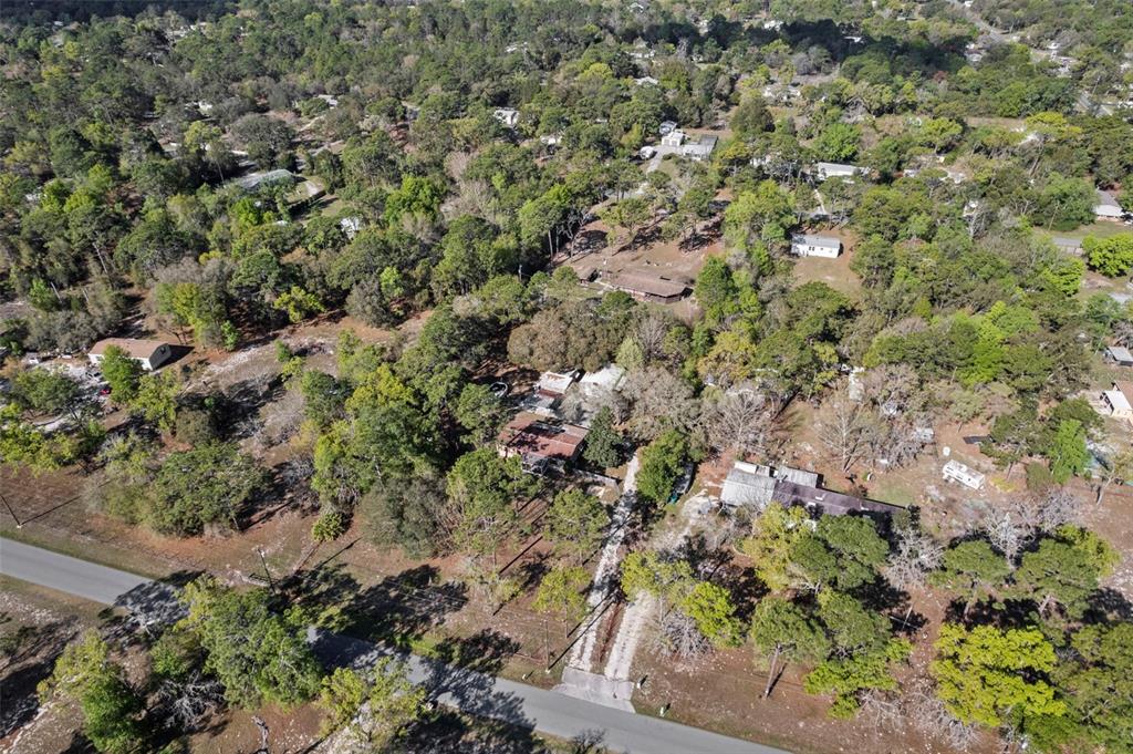 An aerial view shows several houses nestled among dense trees near a paved road — 6850 S MAXWELL POINT, HOMOSASSA, FL