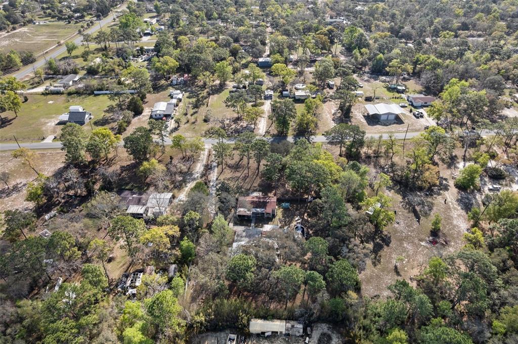 An aerial view shows a rural residential area with scattered houses, trees, and dirt roads — 6850 S MAXWELL POINT, HOMOSASSA, FL
