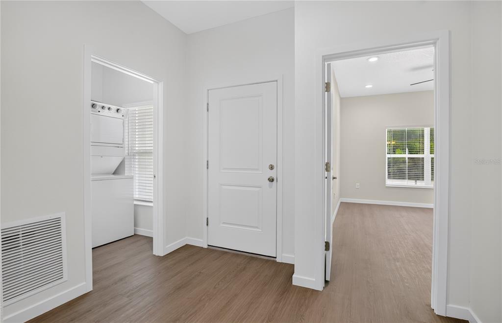 A hallway with wood-look flooring leads to a laundry closet and an adjacent room — 630 NW 59TH AVENUE UNIT 1, OCALA, FL