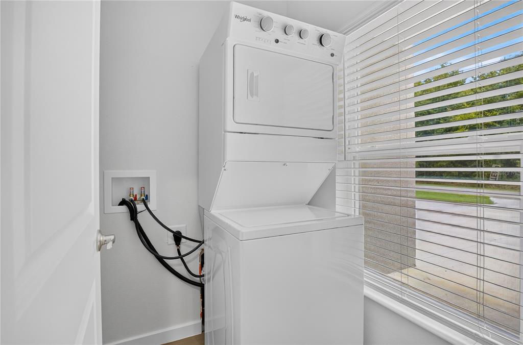 A white stacked washer and dryer unit sits in a laundry room next to a window — 630 NW 59TH AVENUE UNIT 1, OCALA, FL