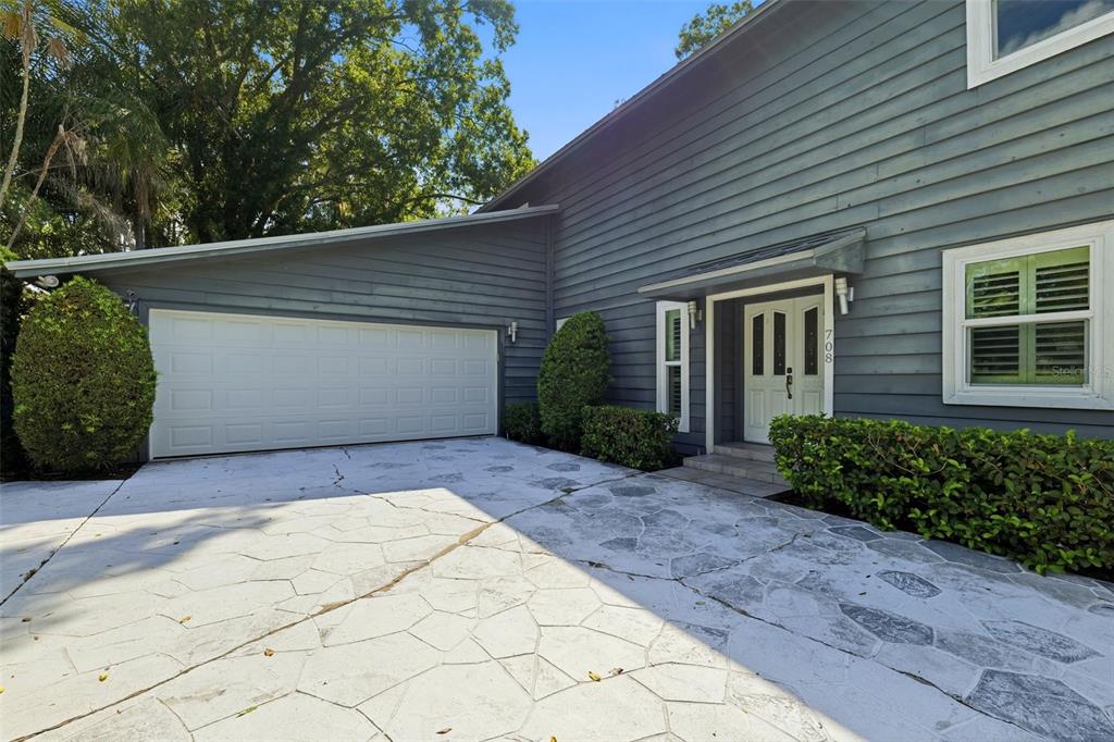 A gray two-story house features a white garage door and a stone-patterned concrete driveway — 708 WARREN ROAD, LUTZ, FL