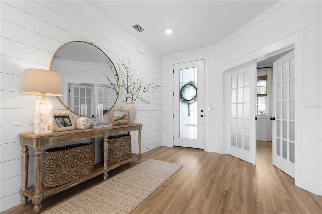 A bright entryway features white shiplap walls, a wooden console table, and light wood flooring — 61 LAS CASITAS BOULEVARD, PALM COAST, FL