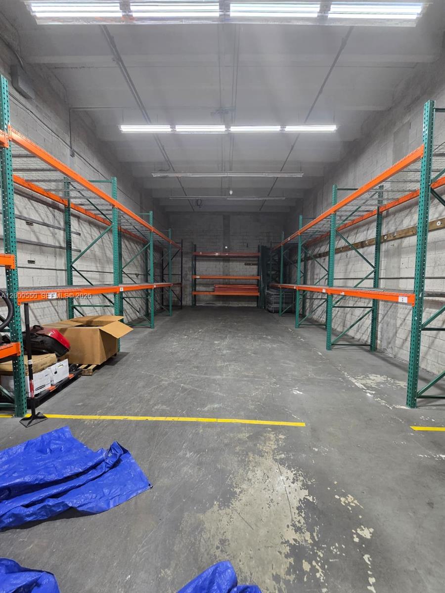 An empty warehouse space features tall metal storage racks along both side walls — 7953 NW 64th St, Medley FL 33166, MEDLEY, FL