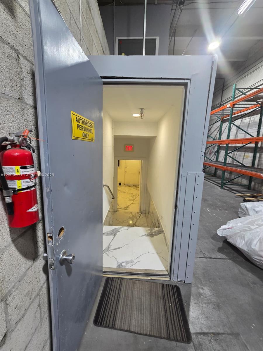 A doorway opens to a stairwell with marble-look flooring leading to an exit sign — 7953 NW 64th St, Medley FL 33166, MEDLEY, FL