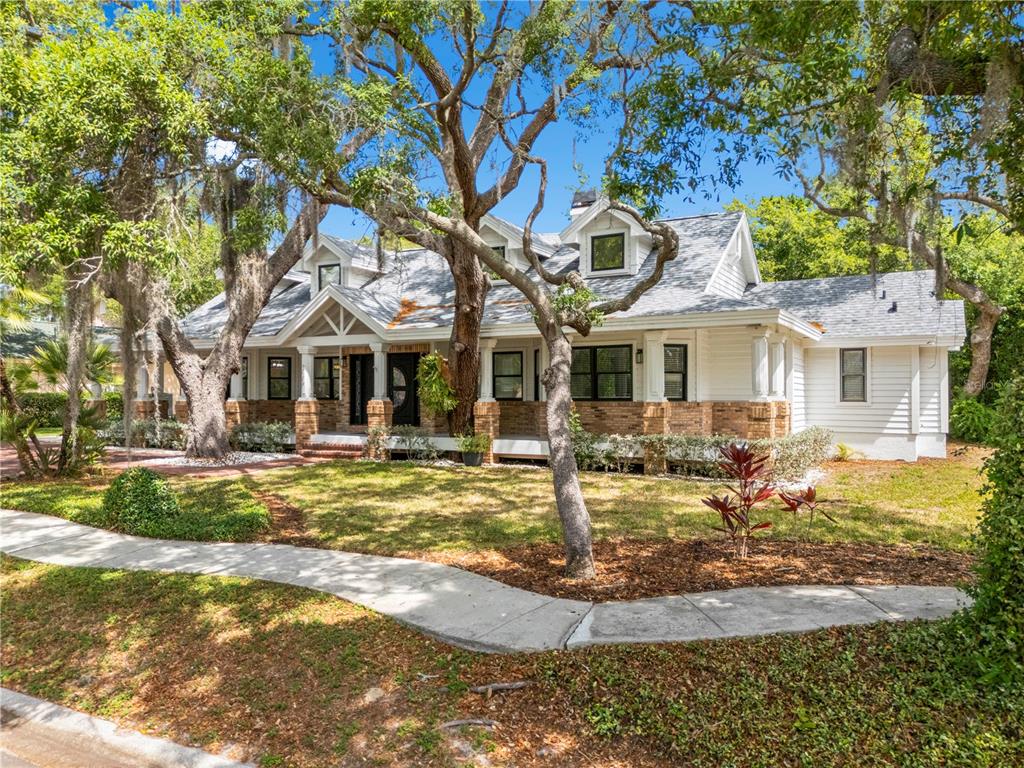 A white house with a brick base and a front porch sits among large trees — 335 SANCTUARY DRIVE, CRYSTAL BEACH, FL