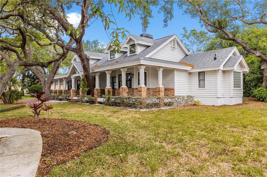 A single-story house with white siding, a brick-based porch, and dormer windows under trees — 335 SANCTUARY DRIVE, CRYSTAL BEACH, FL