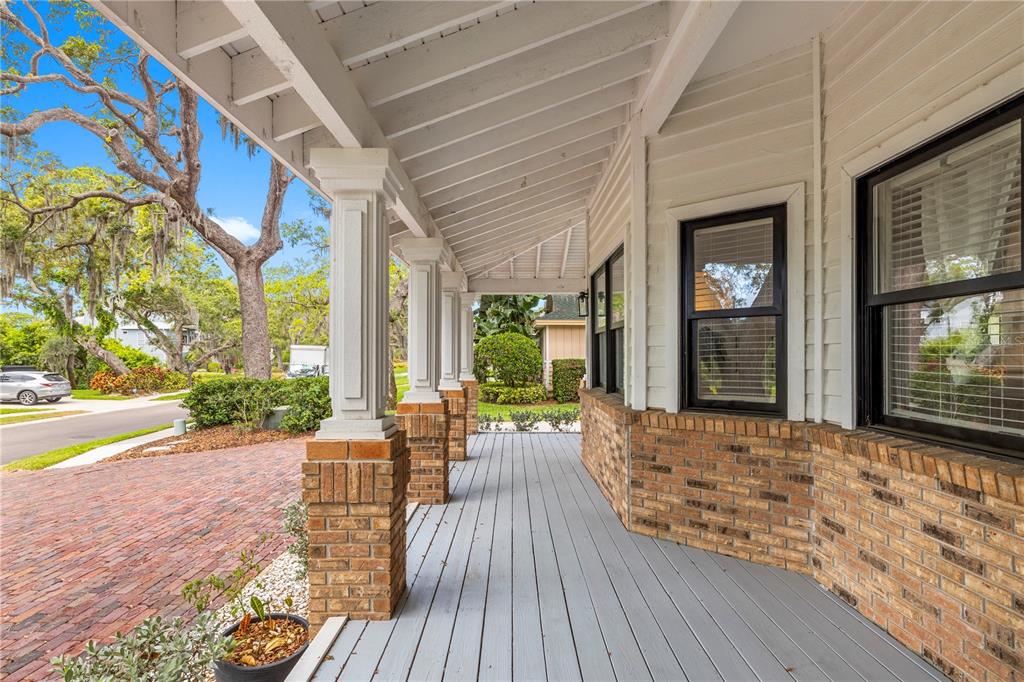 A covered front porch features a gray wooden deck, brick pillars, and white siding — 335 SANCTUARY DRIVE, CRYSTAL BEACH, FL