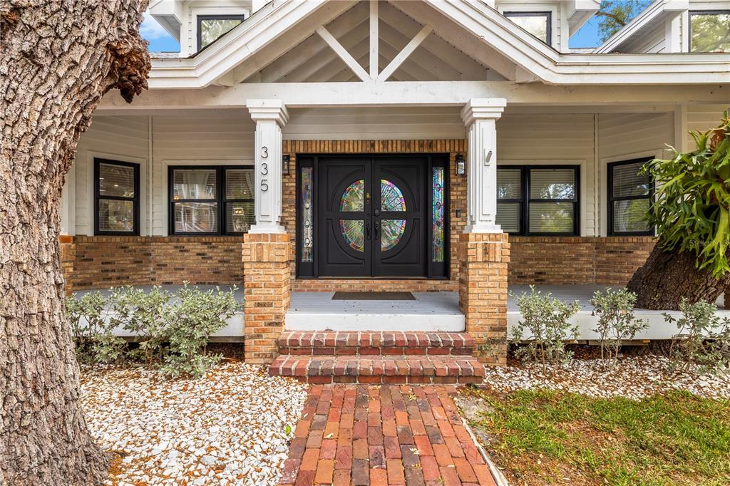 A brick walkway leads to the front porch of a house with a stained-glass door — 335 SANCTUARY DRIVE, CRYSTAL BEACH, FL