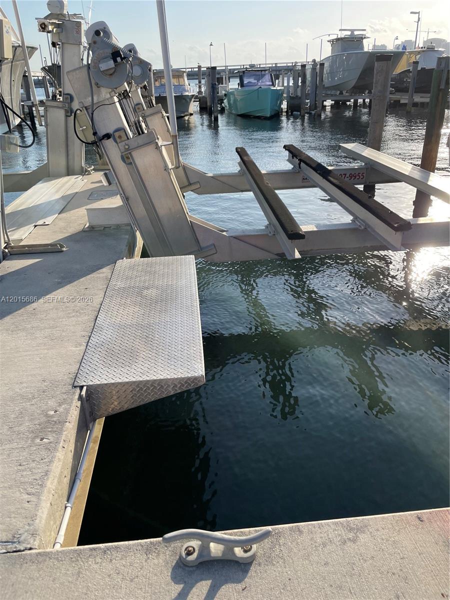 A boat lift with metal tracks extends from a concrete dock into the water — 4 Grove Isle Dr, Miami FL 33133, MIAMI, FL