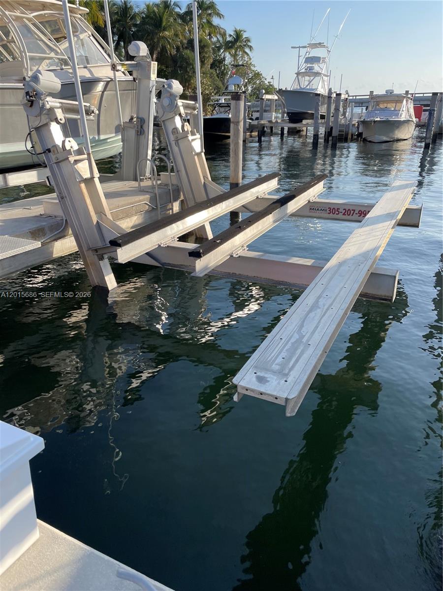 A boat lift with metal rails and black bunks extends over the water — 4 Grove Isle Dr, Miami FL 33133, MIAMI, FL