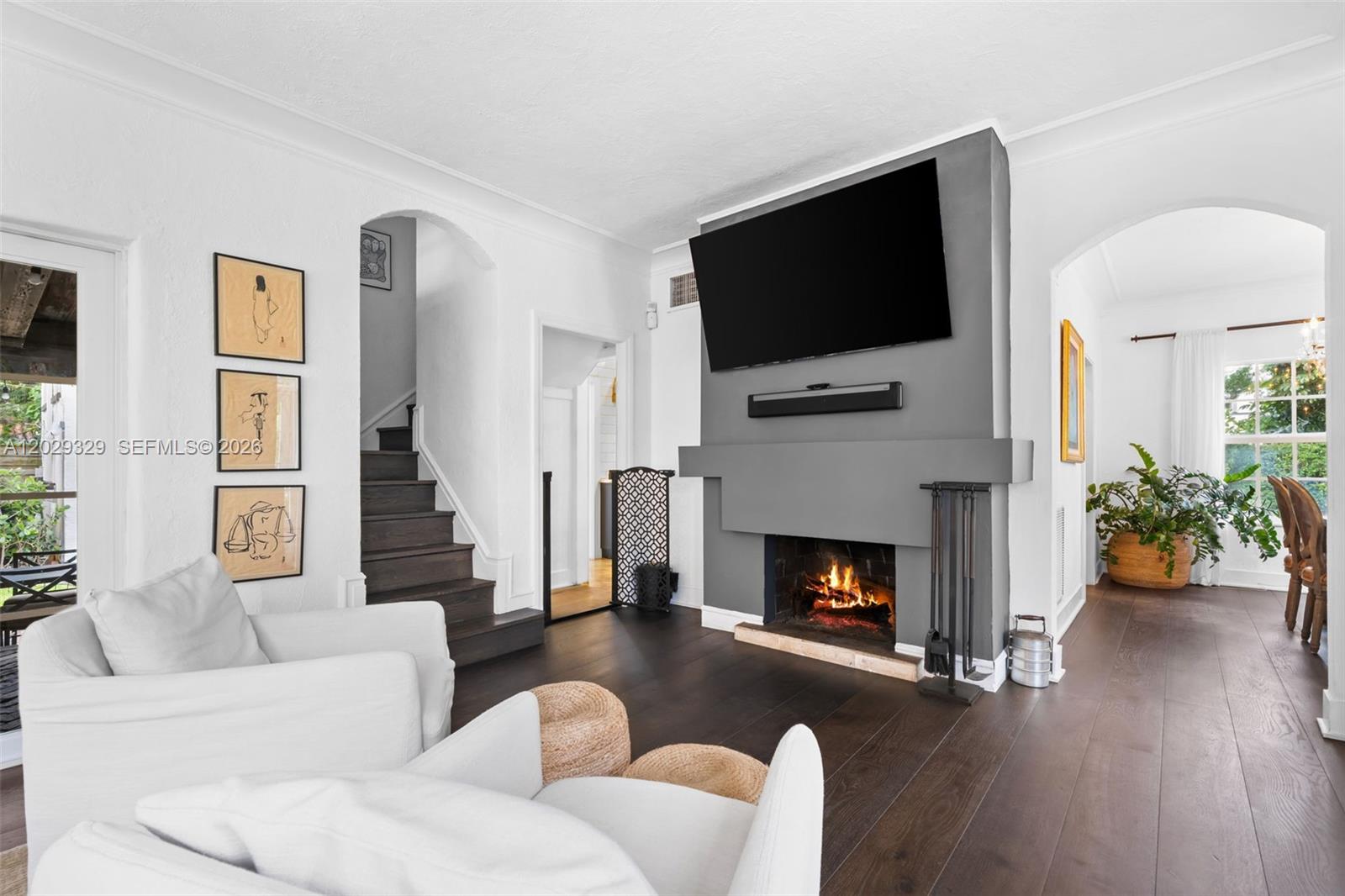 A living room features a gray fireplace with a mounted television and dark wood floors — 646 NE 81st St, Miami FL 33138, MIAMI, FL