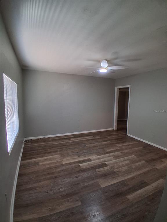An empty room features gray walls, wood-look flooring, a ceiling fan, and a window — 506 N MACDILL AVENUE, TAMPA, FL