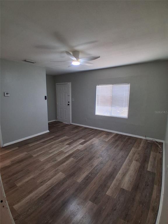 An empty room features gray walls, wood-look flooring, a ceiling fan, and a white door — 506 N MACDILL AVENUE, TAMPA, FL