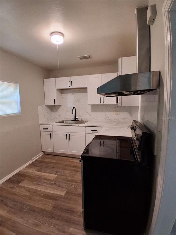 A kitchen features white cabinets, marble-look countertops, a black faucet, and a black electric stove — 506 N MACDILL AVENUE, TAMPA, FL