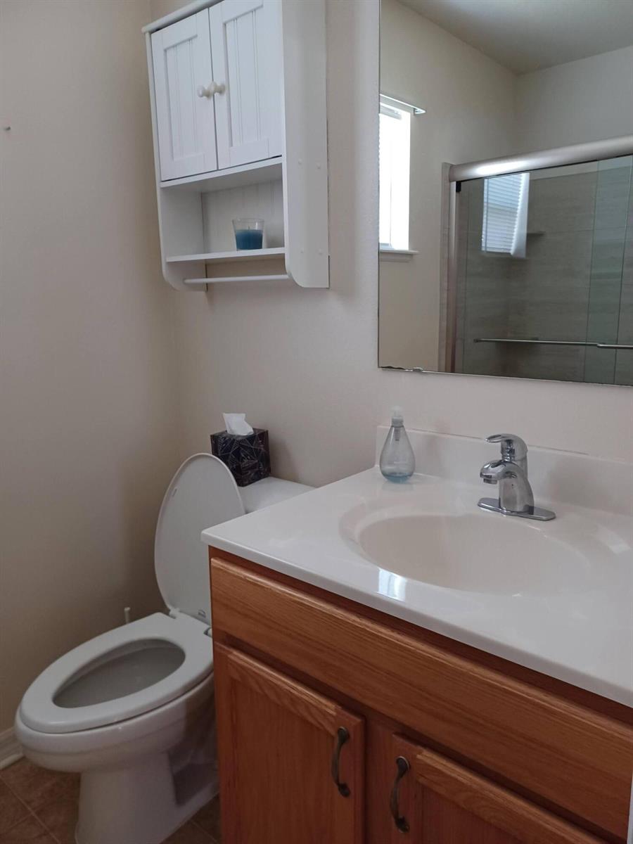 A bathroom features a wooden vanity, a white toilet, and a wall-mounted storage cabinet — 426 Easy Street, Sebastian FL 32958, SEBASTIAN, FL