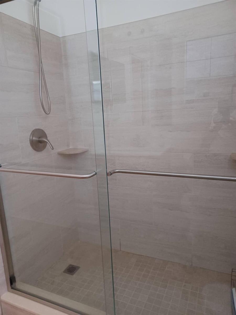 A walk-in shower with a glass door, light-colored tile walls, and a tiled floor — 426 Easy Street, Sebastian FL 32958, SEBASTIAN, FL