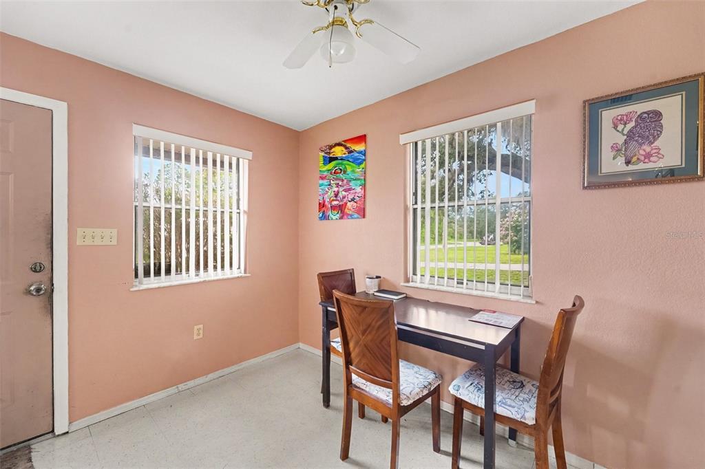 A dining area with peach walls, two windows, a ceiling fan, and a small table — 12155 BAGDAD STREET, SPRING HILL, FL