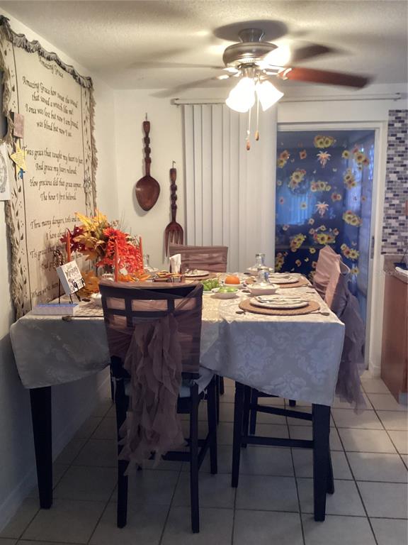 A dining area features a table with place settings, decorative wall hangings, and a ceiling fan — 10029 BRANDYWINE AVENUE, PORT RICHEY, FL
