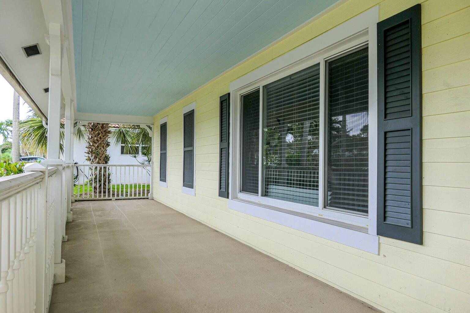 A covered porch with light yellow siding, dark shutters, and a light blue ceiling — 18014 Perigon Way, Jupiter FL 33458, JUPITER, FL