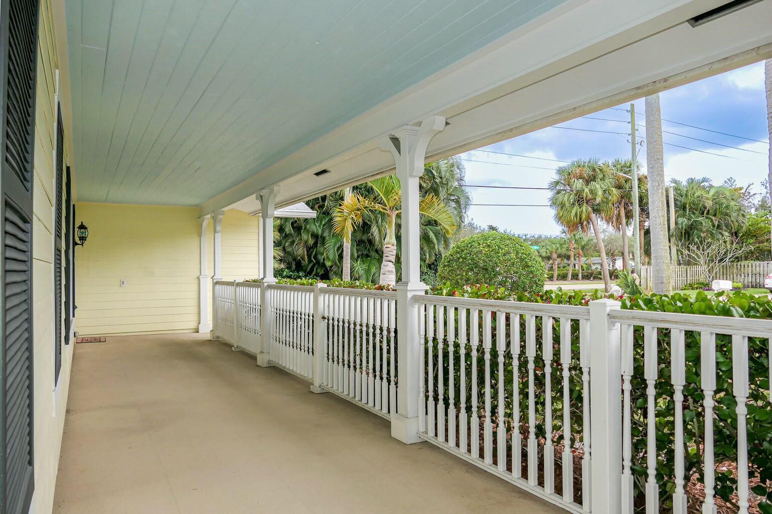 A covered porch with a light blue ceiling, yellow siding, and white wooden railings — 18014 Perigon Way, Jupiter FL 33458, JUPITER, FL