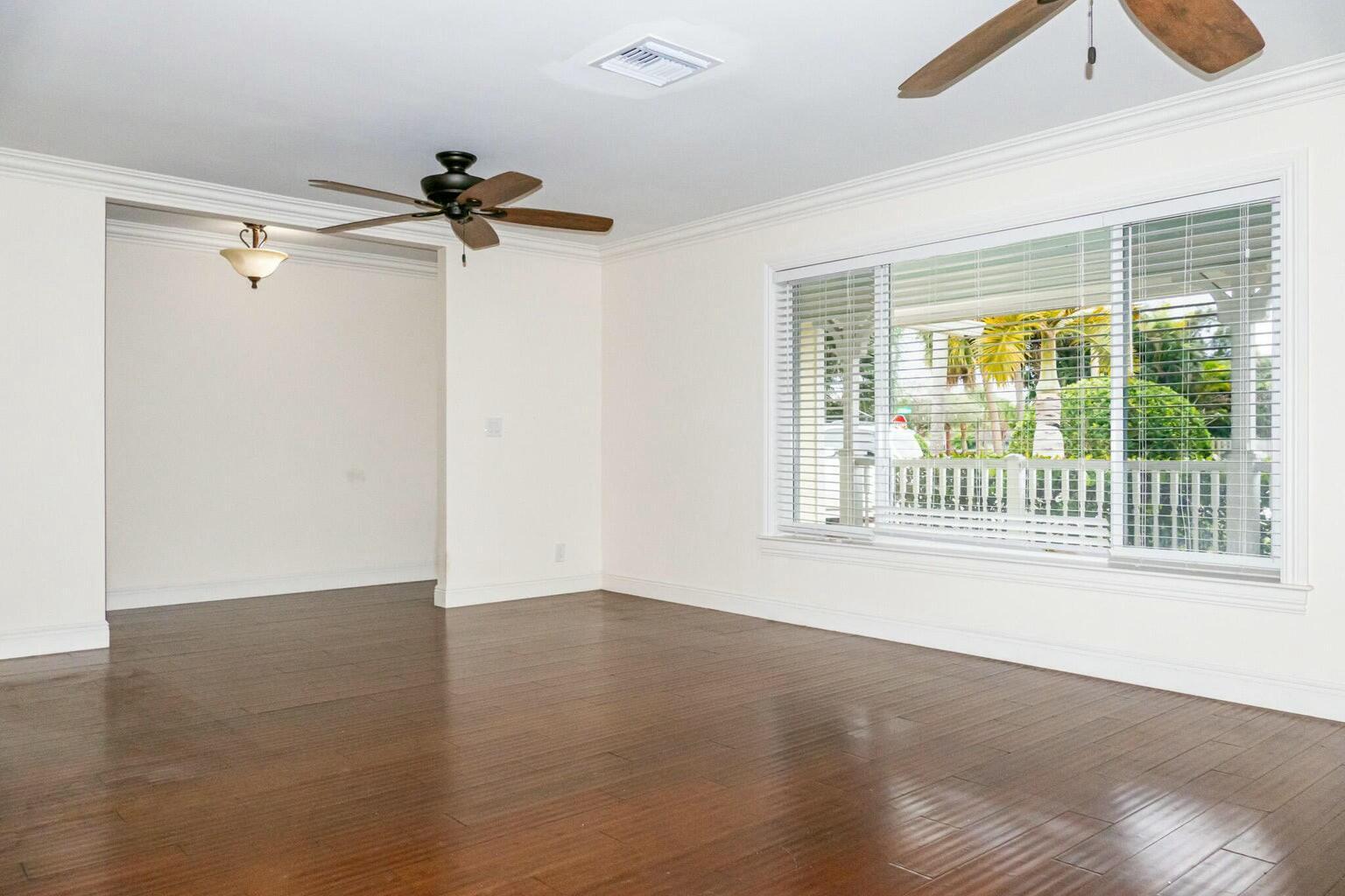 An empty room with dark wood floors, a ceiling fan, and a large window — 18014 Perigon Way, Jupiter FL 33458, JUPITER, FL