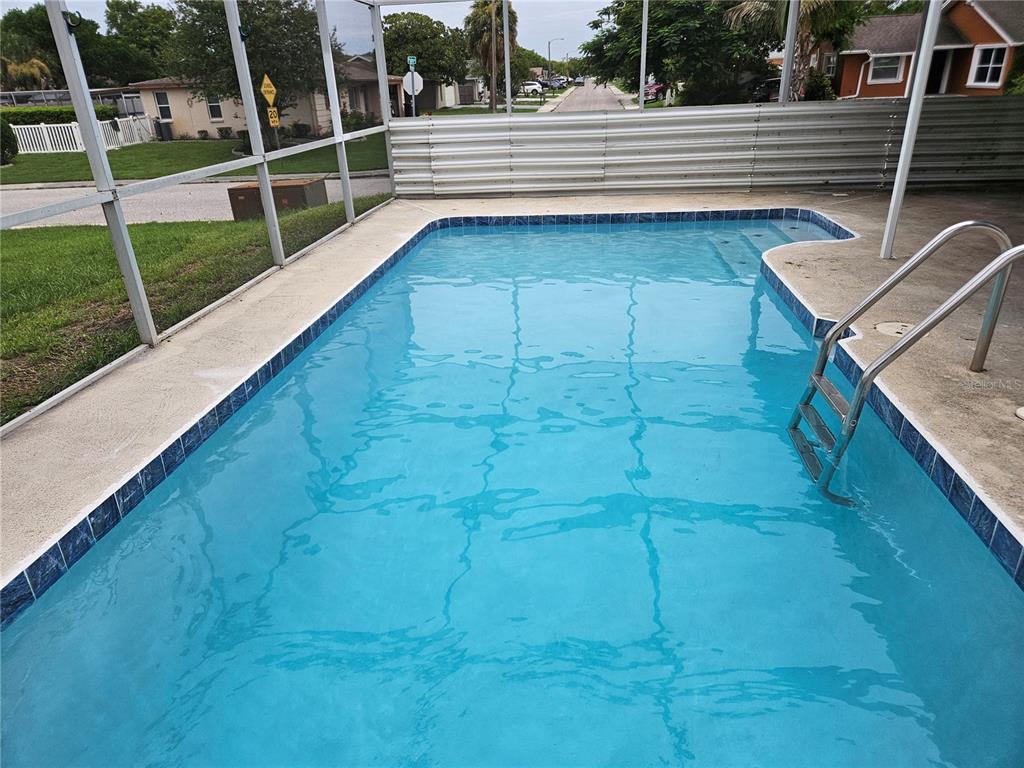 A rectangular swimming pool with a metal screen enclosure and a ladder on the right — 6945 TWILITE DRIVE, PORT RICHEY, FL