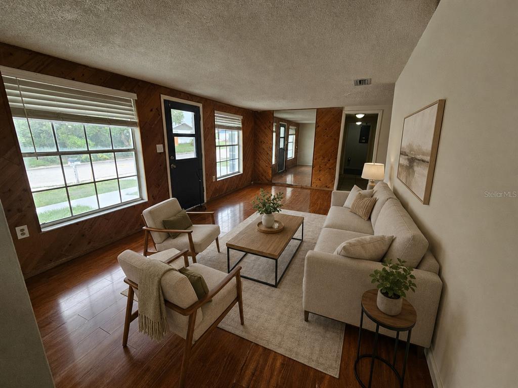 A living room features wood-paneled walls, hardwood floors, a light-colored sofa, and two armchairs — 6945 TWILITE DRIVE, PORT RICHEY, FL