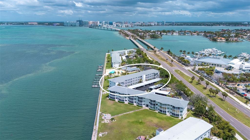 An aerial view shows a multi-story waterfront apartment building circled in white near a bridge — 771 JOHN RINGLING BOULEVARD UNIT 5, SARASOTA, FL