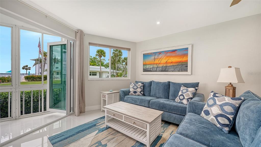A living room features a blue sofa, a wooden coffee table, and a sliding glass door — 771 JOHN RINGLING BOULEVARD UNIT 5, SARASOTA, FL