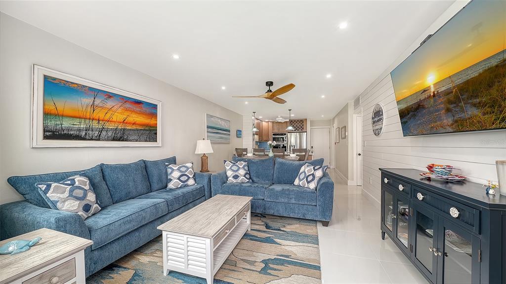 A living room features blue sofas, a white coffee table, and a wall-mounted television — 771 JOHN RINGLING BOULEVARD UNIT 5, SARASOTA, FL